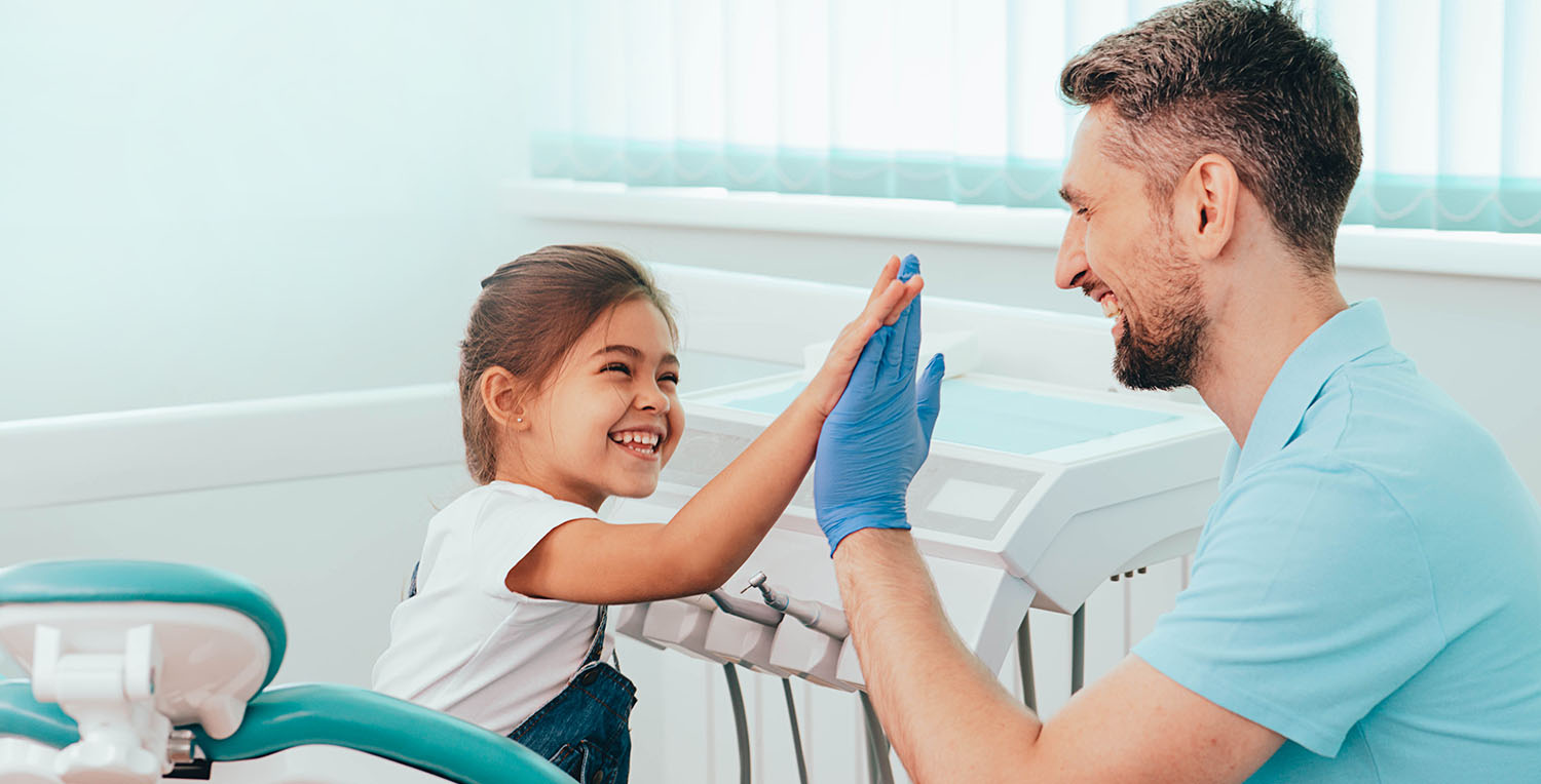 A dental professional high fiving a young patient